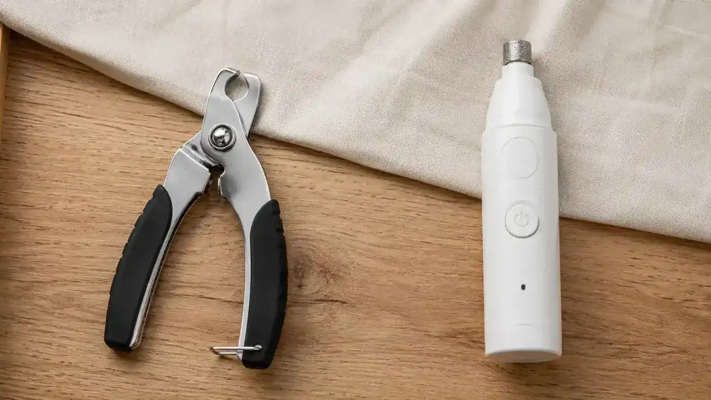 Side-by-side of traditional nail clippers and a modern electric nail grinder on a wood surface